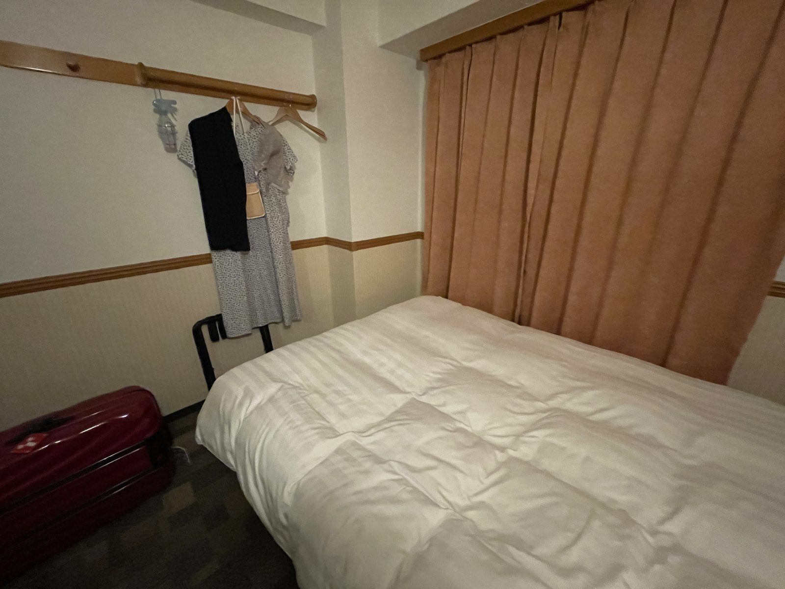 前泊した東横INNの部屋、ベッドのそばに置かれた赤いスーツケース