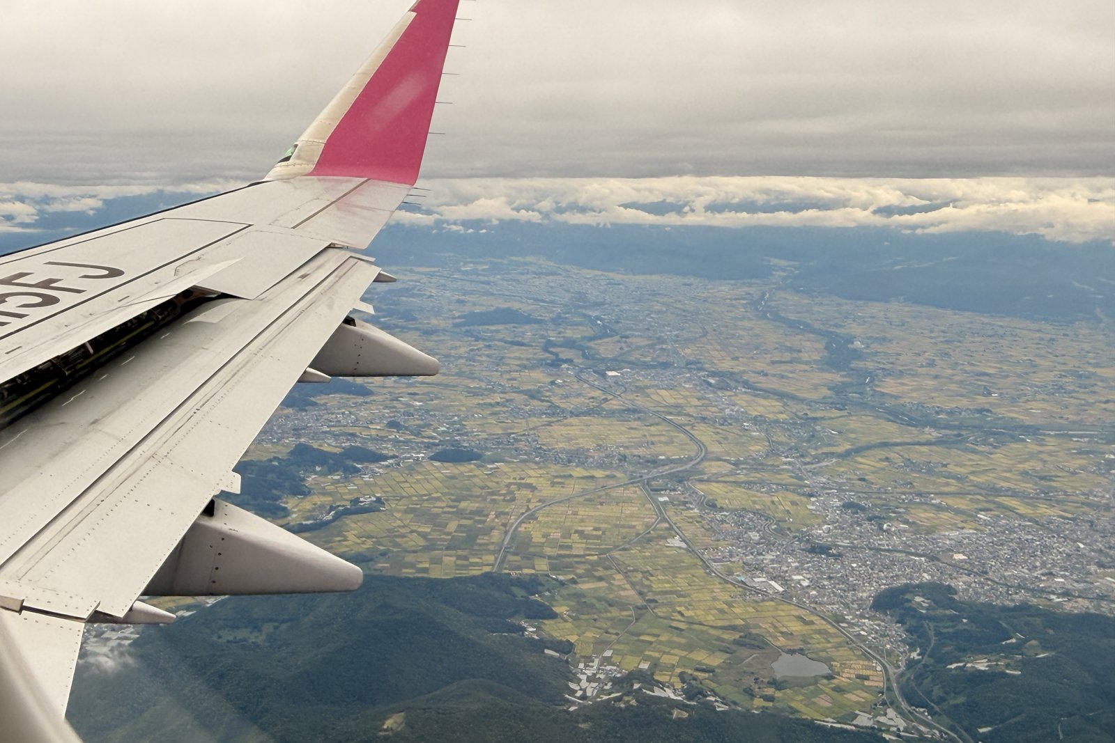 FDAの窓から見下ろした山形の田んぼと町並み、ピンクの翼の先